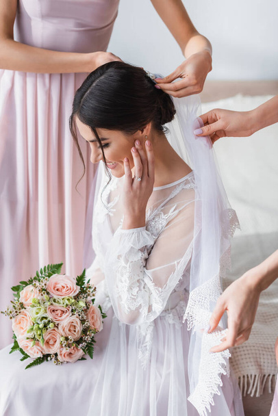 花嫁介添人結婚式の花束を保持幸せな花嫁のベールを固定 ロイヤリティフリー写真 画像素材