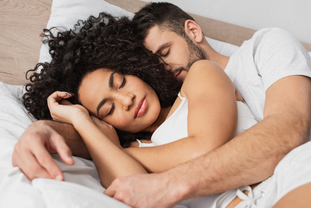 ベッドで寝ている間に抱きつく多民族の男と女 ロイヤリティフリー写真 画像素材