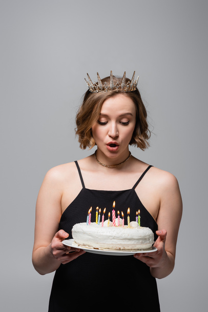 驚くべきプラスサイズの女性にスリップドレスと王冠を保持誕生日ケーキグレーに隔離された ロイヤリティフリー写真 画像素材